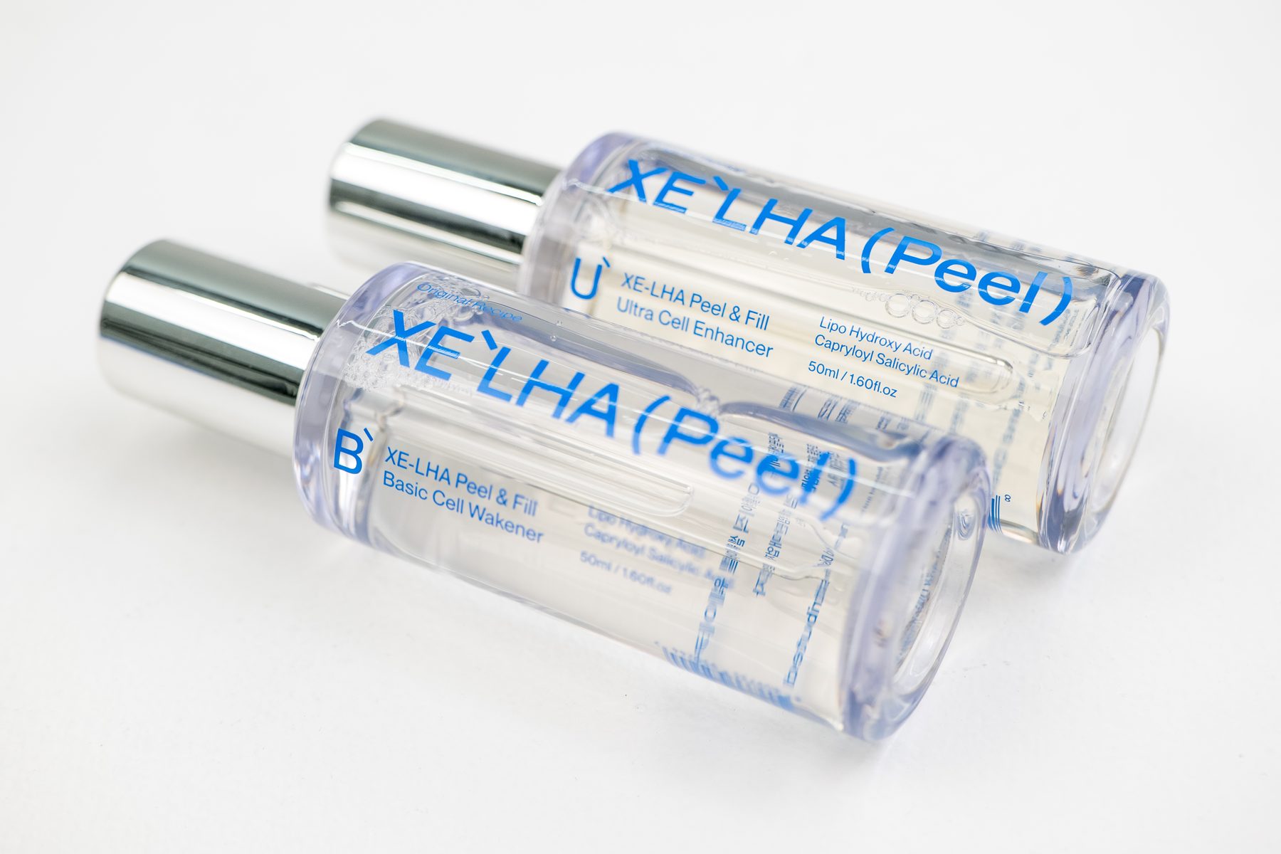 Two XE'LHA Peel bottles lying side by side